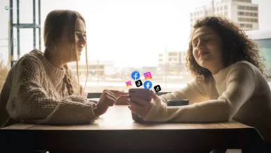 Two women using a smartphone with social media icons.