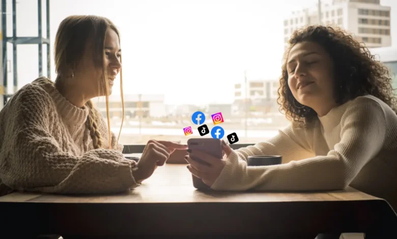 Two women using a smartphone with social media icons.