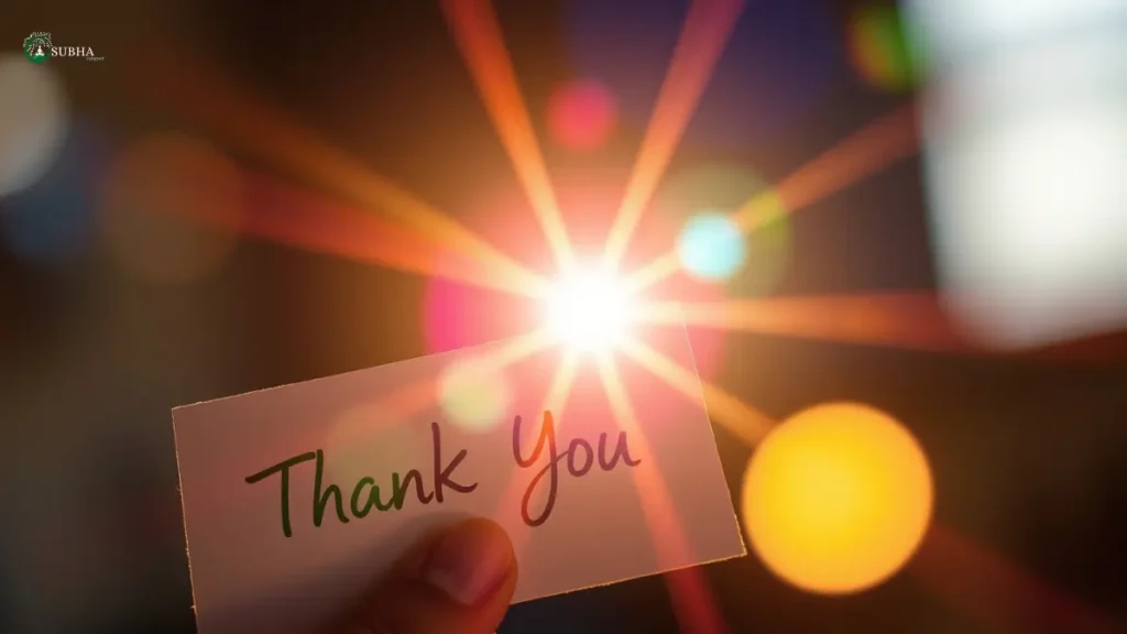 A hand holding a "Thank You" card with bright, colorful light flares in the background.