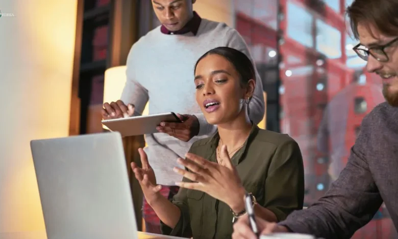Young professionals multitasking during a meeting, highlighting how constant digital distractions impact focus at work